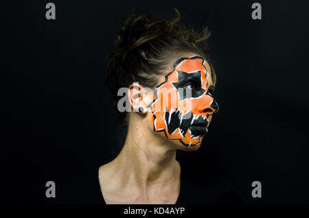 Halloween volto ritratto di vernice su sfondo nero. mostra donna vestito come jack o lantern costume americano per la vacanza. Foto Stock