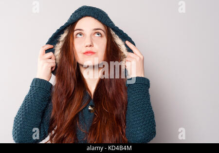 Una bella donna felice con capelli lunghi vestito con una maglia di caldo blu-verde felpa o rivestire con una cappa riscaldata con pelliccia bianca. ragazza guarda. caldo Foto Stock