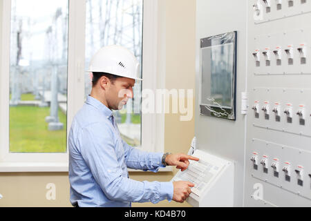 Ingegnere industriale utilizzando la tastiera in corrispondenza della stazione di alimentazione. ingegnere di lavoro in studio di luce. Foto Stock