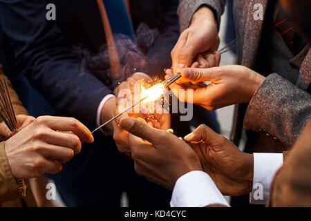 Le mani dei giovani in giacca tenendo la masterizzazione sparkles fuochi d'artificio Foto Stock