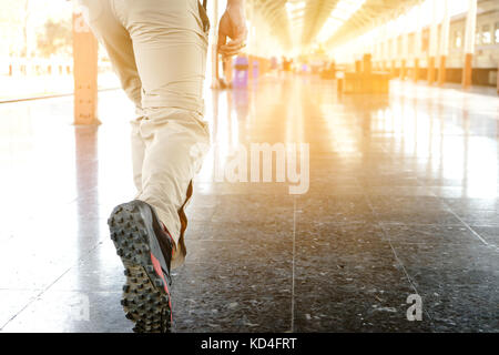 Uomo che cammina in una stazione ferroviaria per iniziare il suo programma di viaggio Foto Stock