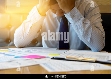 Imprenditore sedersi al lavoro impegnativo tabella egli riempire stanchi e mal di testa Foto Stock