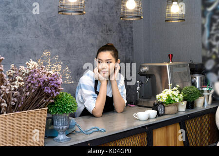 Una donna asiatica in piedi in un contatore di coffee shop barista e proprietario del negozio Foto Stock