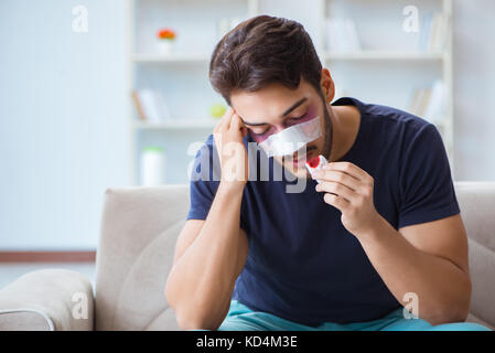 Giovane uomo recuperando la guarigione a casa dopo un intervento di chirurgia plastica naso job Foto Stock