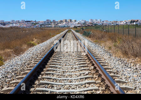 Una vista lungo la linea ferroviaria che corre lungo il sud del Portogallo costa. la famosa città turistica di lagos è in distanza. Foto Stock