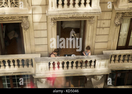 Due ragazze sui loro telefoni cellulari su un balcone a madrid Foto Stock