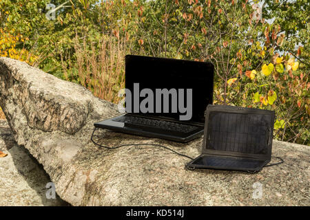 Pannello solare per ricaricare un computer portatile in un remoto la posizione di lavoro. Foto Stock