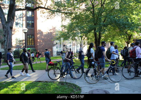 Una folla di manifestanti cammina lungo la strada con le biciclette al campus Ann Arbor della University of Michigan nel centro di Ann Arbor, Michigan Foto Stock