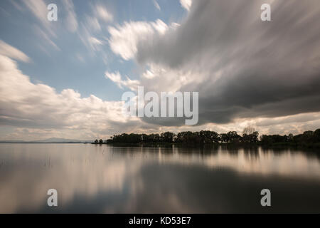 Una lunga esposizione vista di un lago con lo spostamento delle nuvole bianche rispecchiando perfettamente su acqua Foto Stock