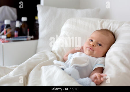 Carino bambino giacente a letto con il freddo e la febbre Foto Stock