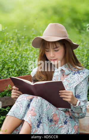 Bella donna asiatica rilassante leggendo prenota in posizione di parcheggio Foto Stock