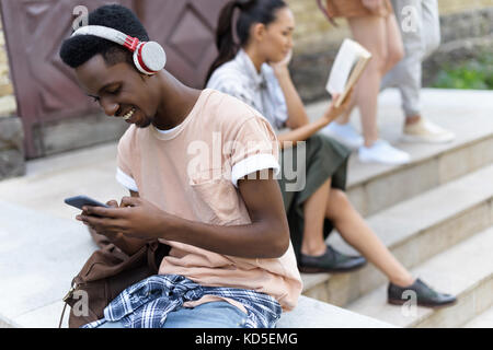 Studente utilizza lo smartphone e le cuffie Foto Stock