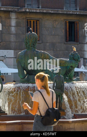 Donna viaggio da solo concetto, vista posteriore di una giovane donna che naviga per telefono mentre cammina attraverso la Plaza de la Virgen a Valencia, Spagna. Foto Stock