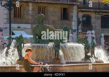 Spagna città estate, vista di una donna che cavalcano la sua bicicletta passando la Fontana Turia in Plaza de la Virgen nel centro di Valencia in una giornata estiva, la Spagna. Foto Stock