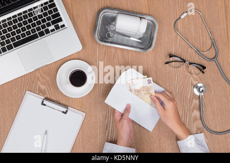 Vista superiore del medico parlando denaro dal suo paziente. Foto Stock