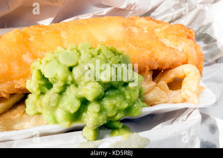 Pesce e patatine con fiacco piselli, avvolto in carta da un takeaway, UK. Foto Stock