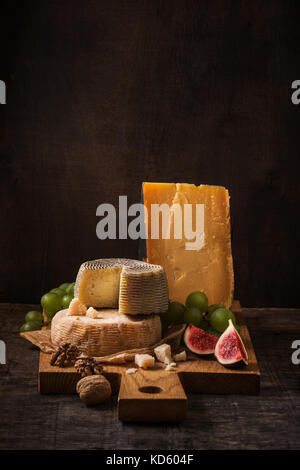 Scheda di formaggio, frutta e i dadi sul legno ruvido Foto Stock