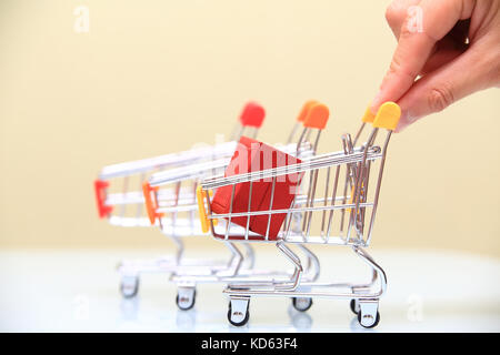 Vendita di natale concetto. mano trattiene piccolo carrello con confezione regalo rossa close-up. Foto Stock