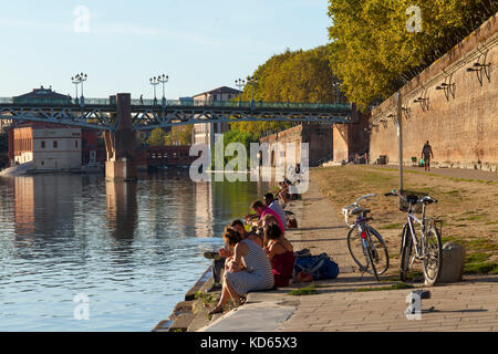 Tolosa (Francia meridionale): a piedi e relax lungo le sponde del fiume Garonna in estate, visto dal "quai de la Daurade' quay. Persone sitt Foto Stock