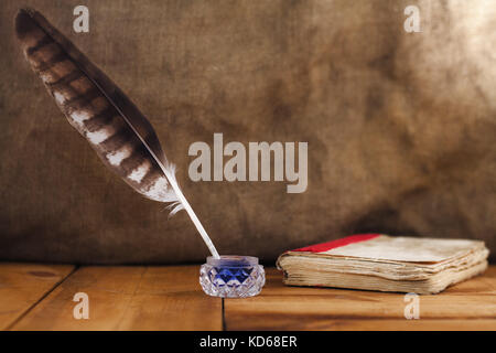 Quill penna, bottiglia di inchiostro e vecchio libro, ripresa dall'alto su una tavola di legno texture di sfondo, il concetto di studiare o di scrittura; gli oggetti vintage Foto Stock