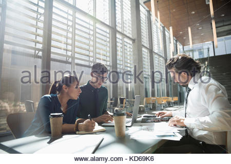 Uomini d'affari che si incontrano, lavorano al computer portatile in un ufficio soleggiato