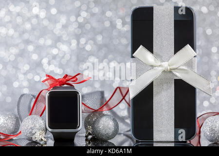 Smartphone e smartwatch e decorazioni per albero di Natale di vetro nero tabella. concentrarsi sullo smartphone. Foto Stock