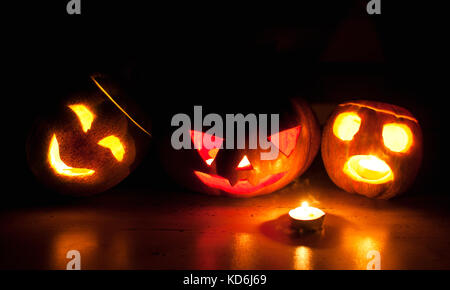 Scary Halloween zucca e melone jack-o-lanterne su sfondo nero illuminato con piccola rotonda e star candele. Il fuoco selettivo bokeh di fondo. Foto Stock