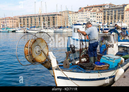 Fisherman tirando il pesce al di fuori della rete in Vieux Port (porto vecchio) sul giorno di mercato, Marsiglia, Francia Foto Stock