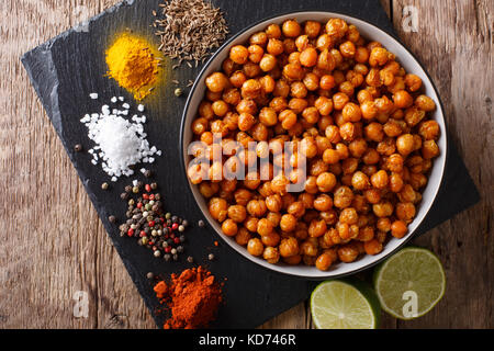 Arrosto speziato i ceci in una terrina e gli ingredienti sul tavolo di close-up. parte superiore orizzontale vista da sopra Foto Stock