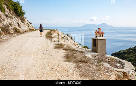 Una femmina di walker passando un santuario stradale nella forma di una chiesa sull isola di Itaca nelle isole Ionie Foto Stock