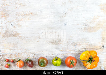 Confine di antiche varietà di pomodori dal piccolo al bigest su vecchi dipinti di bianco sullo sfondo di legno spazio copia Foto Stock