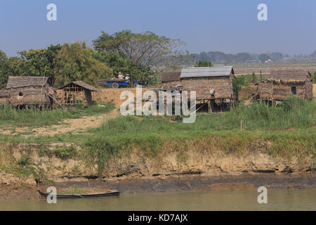 Un piccolo camion che trasportano pali di legno che passa attraverso un villaggio sul fiume Irrawaddy in Myanmar (Birmania). Foto Stock