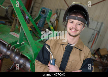 Felice apprendista saldatore a lavorare nell'impianto Foto Stock