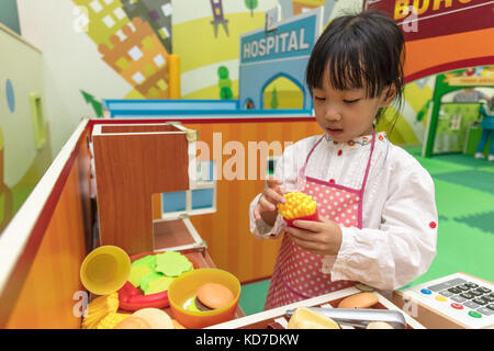 Cinese asiatici bambina role-playing a burger store al parco giochi al coperto Foto Stock