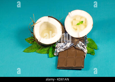 Cioccolato, noci di cocco e praline di cocco su uno sfondo di legno Foto Stock