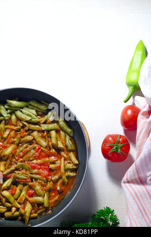 Cotti fagioli verdi con salsa di pomodoro su sfondo bianco Foto Stock