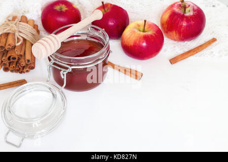 Il miele nel vasetto di vetro e apple con bastoncini di cannella su sfondo bianco Foto Stock