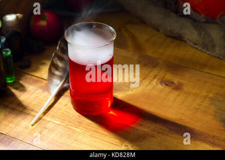 Pozione rosso con il fumo o la nebbia su sfondo di legno Foto Stock
