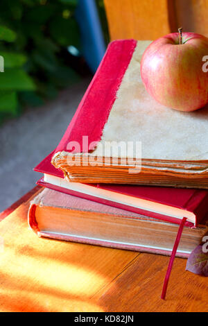 Si torna a scuola concetto. Lavagna con libri e apple sullo sfondo di legno. Foto Stock