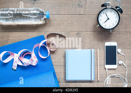 Palestra e fitness concetto con notebook, smartphone e sveglia su sfondo di legno Foto Stock