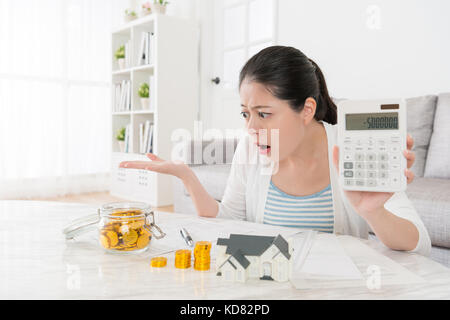 Infelice giovane madre utilizzando la calcolatrice mostra il numero negativo quando lei nuovo piano casa e famiglia di conteggio salvataggio di constatazione non basta sentirsi sconvolto. Foto Stock