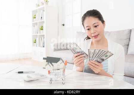 Bellezza Donna attraente conteggio banconote in contanti del denaro in salotto e la pianificazione utilizzando deposito acquista una nuova casa per la famiglia. Foto Stock