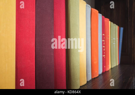 Libri antichi in luminose colorate copre stand in una fila sullo scaffale di legno Foto Stock