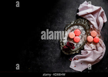 Macarons su un piatto d'argento contro un oscuro bckground Foto Stock
