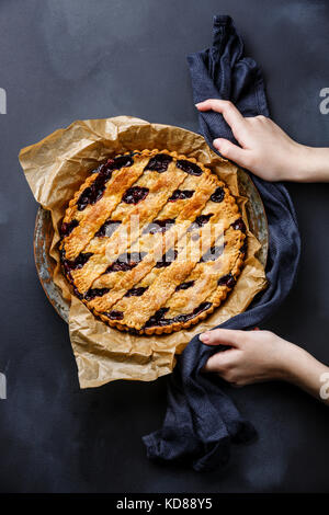 Cherry Pie e le mani femminili su sfondo in ardesia lavagna Foto Stock