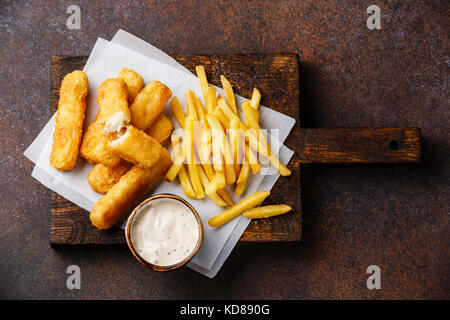 I bastoncini di pesce e patatine british fast food con salsa tartara su sfondo scuro Foto Stock