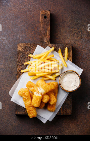 I bastoncini di pesce e patatine british fast food con salsa tartara su sfondo scuro Foto Stock