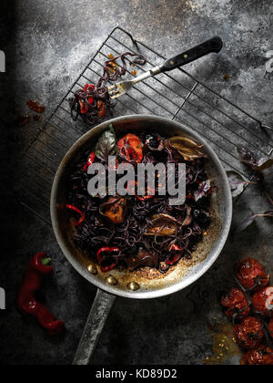Pan rustico riempita con nero, seppia pasta e pomodori arrostiti al buio su un superficie rustico.