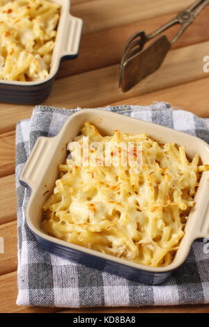 Mac e formaggio blu in una teglia su blu e bianco asciugamano a scacchi con argento vecchio raccoglitrice di pasta Foto Stock