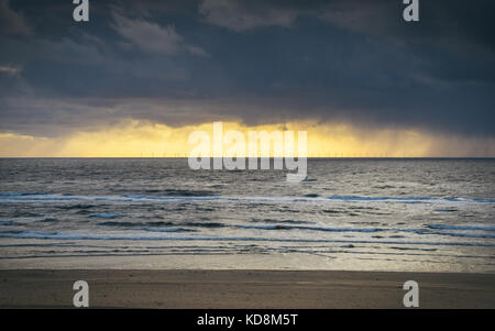 Nuvole di tempesta che si affaccia Zandvoort in Olanda. elettrico di mulini a vento sono visibili nel lontano sullo sfondo Foto Stock